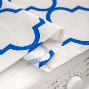 Detailed view of blue geometric pattern dust cover fabric on washing machine surface