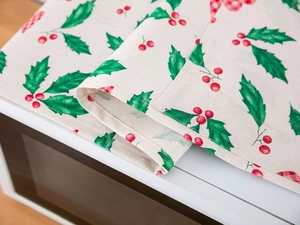 Close-up of linen microwave cover with festive holly berries and red plaid patterns