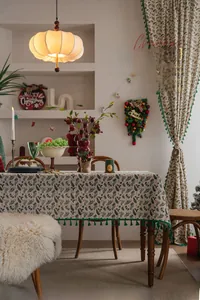 Close-up of festive holly leaf and red berry print tablecloth with green fringe trim