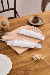 Detail of white cotton linen placemats with blue embroidered lace on a wooden tray