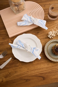 Detailed view of silver leaf-shaped napkin rings on a white cloth with blue stripes