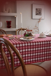 Close-up of red and white checkered tablecloth featuring decorative pom-pom fringe edges