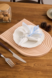 Close-up of silver leaf napkin rings on white cotton napkins with blue embroidery