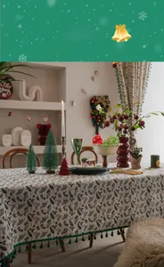 Close-up of festive Christmas tablecloth with holly berry print and green tassel fringe