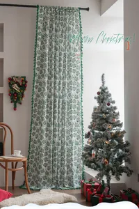 Detail of Christmas curtain featuring green holly leaves and white pom-pom fringe trim