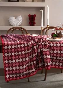 Close-up of red and white jacquard tablecloth with festive pompoms on wood table