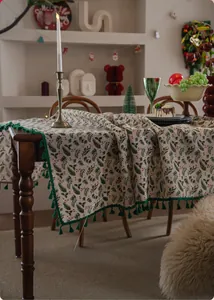 Detail of Christmas tablecloth featuring holly leaf patterns and green tassel edges