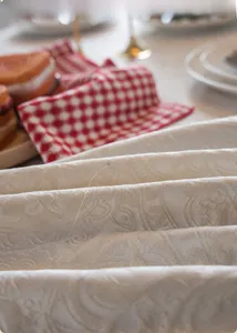 Macro detail of luxury white jacquard tablecloth with textured 3D floral pattern embroidery