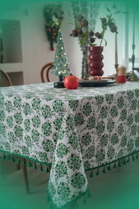 Close-up of Christmas tablecloth with green floral patterns and dark green fringe details