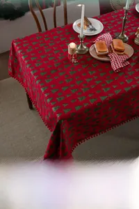 Detail der roten Weihnachtstischdecke mit goldenen Bäumen und festlicher Pompon-Bordüre