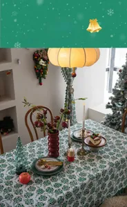 Close-up of Christmas tablecloth with green floral gold foil print on festive dining table
