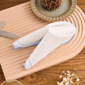 French style white cotton linen napkin with blue embroidered wavy edges on wooden tray