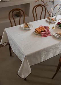 Close-up of luxury jacquard tablecloth with textured 3D floral patterns and wavy brown edges