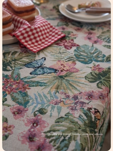 Macro view of woven jacquard tablecloth featuring monstera leaves and pink floral motifs