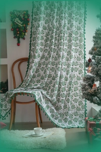 Detail of white floral curtain with green leaf pattern and emerald tassel fringe trim