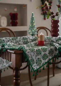 Close-up of Christmas tablecloth featuring green floral prints and elegant tassel edges