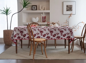 Dettaglio di motivi floreali jacquard rossi su tovaglia avorio con bordo a smerlo