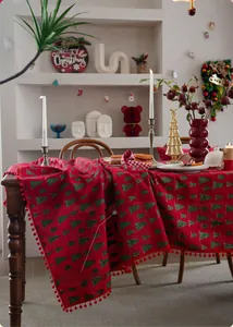 Detail der roten Weihnachtstischdecke mit grünen Baummustern und Bommelfransen