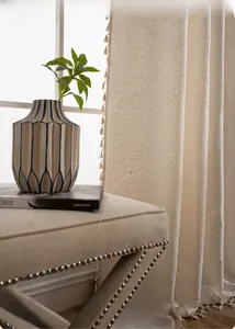 Detailed view of cream paisley jacquard curtain fabric with decorative fringe edging