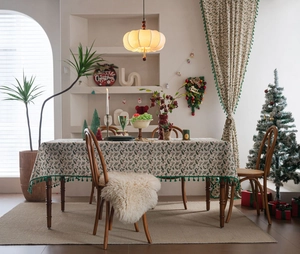 Close-up of festive Christmas holly leaf tablecloth with green tassels and matching curtains