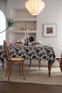 Dettaglio tovaglia jacquard con motivo floreale nero e trama di fiori ricamati su tavolo