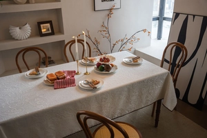 Detailed view of embossed floral texture and scalloped edges on cream tablecloth