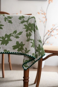 Detailaufnahme der Jacquard-Tischdecke mit grünem Blattmuster und dunkelgrünem Wellenrand