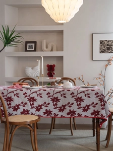 Dettaglio della tovaglia jacquard crema con motivi floreali rossi e bordi ondulati