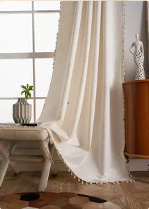 Detailed close-up of cream jacquard curtain fabric with fringe trim and paisley pattern
