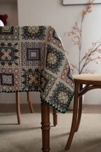 Dettaglio di tovaglia jacquard vintage con motivi geometrici e pizzo verde ondulato