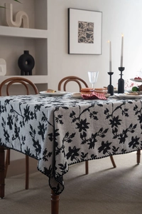 Dettaglio del ricamo floreale nero e del bordo ondulato sulla tovaglia jacquard