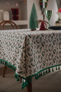 Detail of Christmas holly leaf tablecloth with green tassels and festive berry print