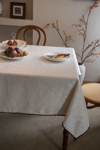 Detail of white paisley jacquard tablecloth with elegant dark wavy scalloped edge