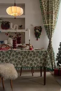 Detail of Christmas tablecloth with holly leaves, red berries and green pom-pom tassels