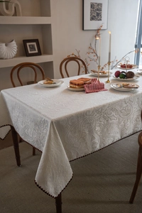 Detail of cream paisley jacquard tablecloth with scalloped edges and beaded fringe trim
