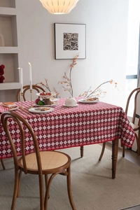 Detail of red and white lattice tablecloth featuring pom-pom tassel edges in cozy setting