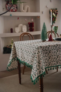 Detail of Christmas holly leaf tablecloth with red berries and green tassel edges