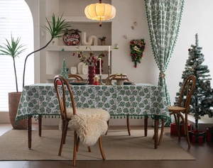 Detailed view of green floral Christmas tablecloth with decorative tassel fringes