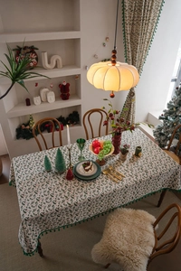 Close-up of Christmas holly leaf tablecloth with festive berries and green pom-pom trim
