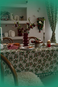 Detail of Christmas tablecloth with holly leaves, red berries, and green tassels fringe