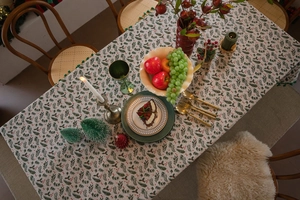 Close-up of festive Christmas tablecloth with holly leaves and red berry prints