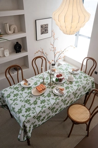 Detailansicht der weiß-grünen Jacquard-Tischdecke mit Blumenmuster auf Holztisch