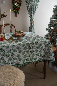 Detailed close-up of Christmas tablecloth with green floral patterns and elegant dark green tassels