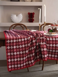 Detail of red and white checkered tablecloth with decorative scalloped edges on a wooden table