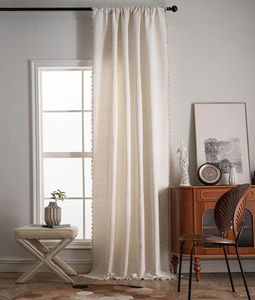 Close-up of cream jacquard curtain fabric with decorative tassels and relief texture