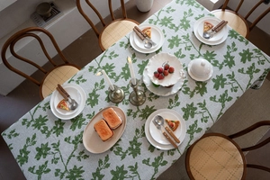 Nahaufnahme der Jacquard-Tischdecke mit grünem Blumenmuster auf rustikalem Esstisch