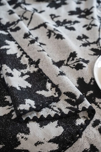 Dettaglio tovaglia jacquard floreale bianca e nera con bordi smerlati all'uncinetto