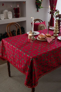 Detail der roten Weihnachtstischdecke mit grünen Baummotiven und weichem Pompon-Besatz