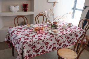 Dettaglio di tovaglia jacquard floreale rossa con bordi ondulati su un tavolo in legno