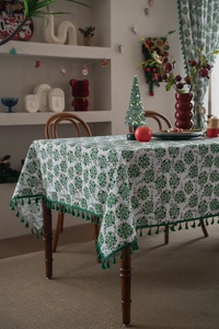 Detail of Christmas tablecloth featuring green snowflake patterns and thick green fringe trim